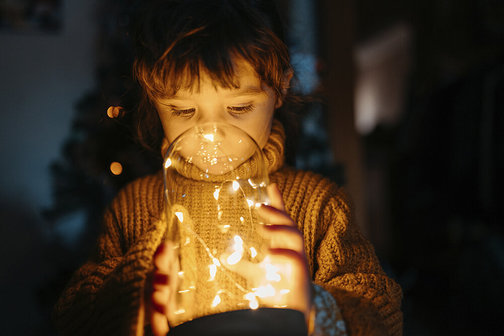 Weihnachtlicher Dekorausch - ein kleines Kind betrachtet ein beleuchtetes Glas.