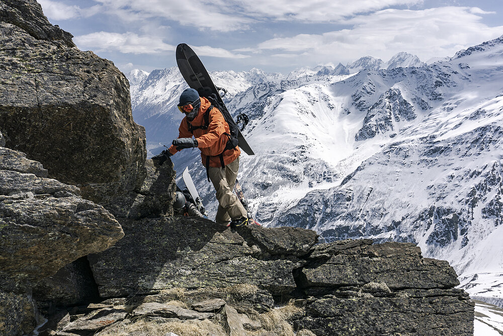 Mann klettert auf einen Berg für das besondere Ski-Vergnügen.
