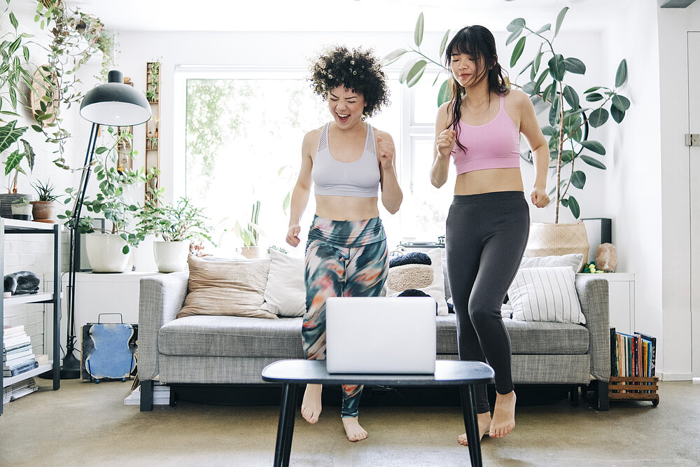 Two young women are doing a workout in the living room.
