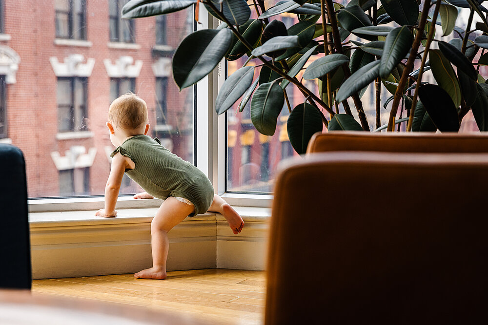Zimmer mit Aussicht - Kleinkind guckt aus einem Fenster.