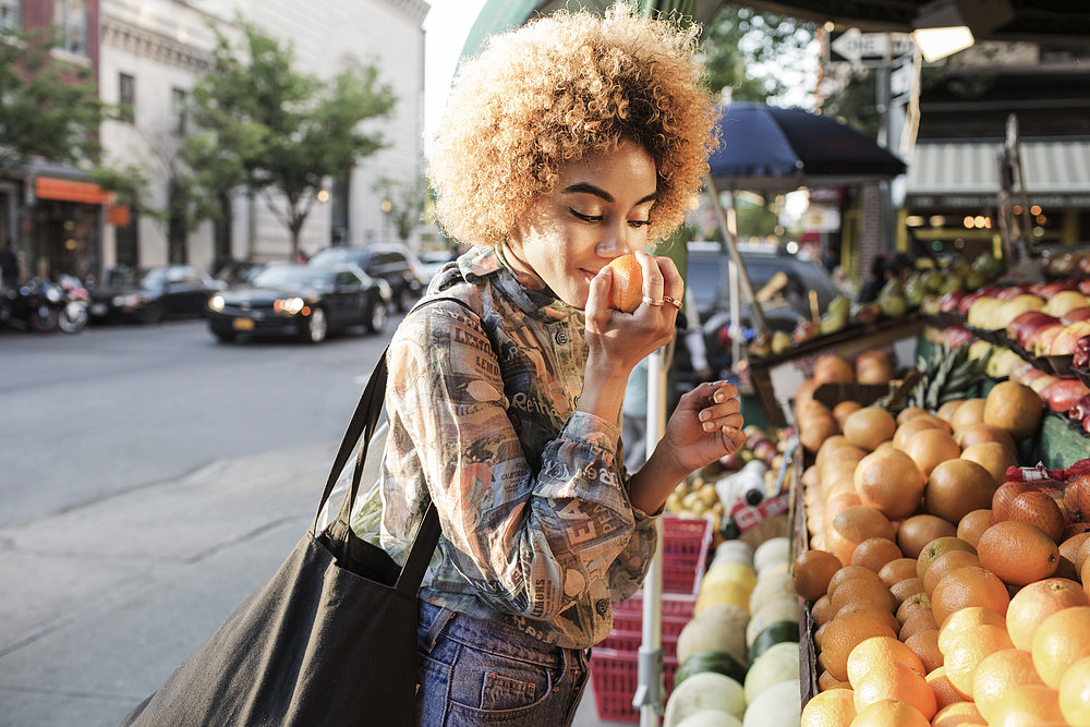 Frau riecht an einem Markttag an frischem Obst.